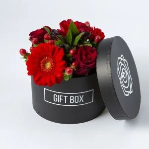 Rood bloemstuk in zwart hoedendoosje bovenaf